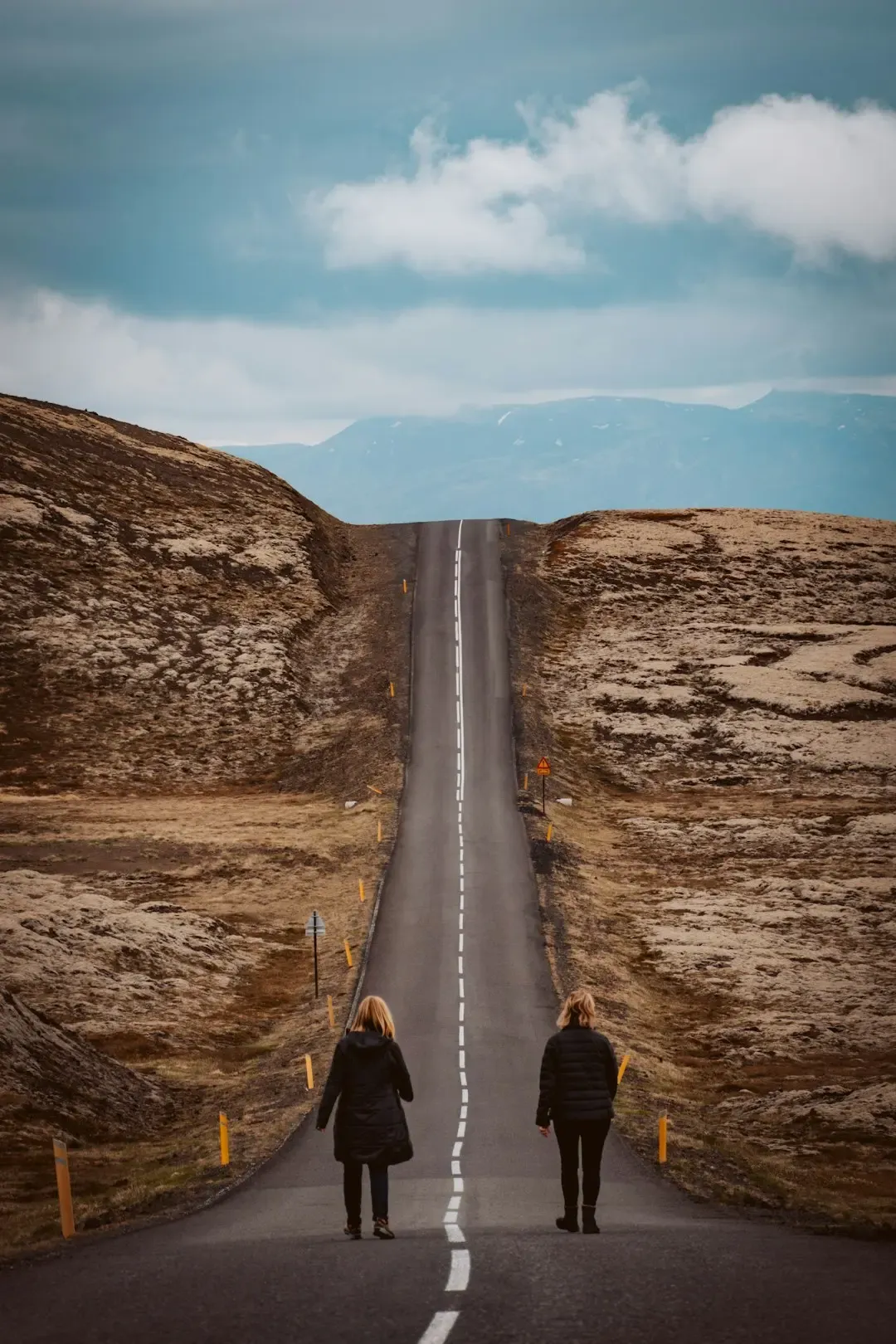 A person walking along an open road towards the horizon