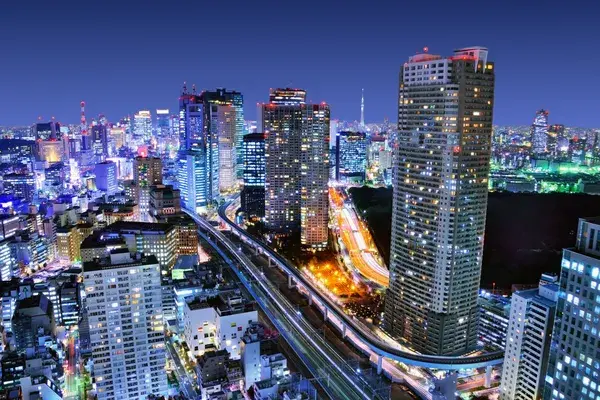 City skyline lit up at night with an elevated railway curving between the towers